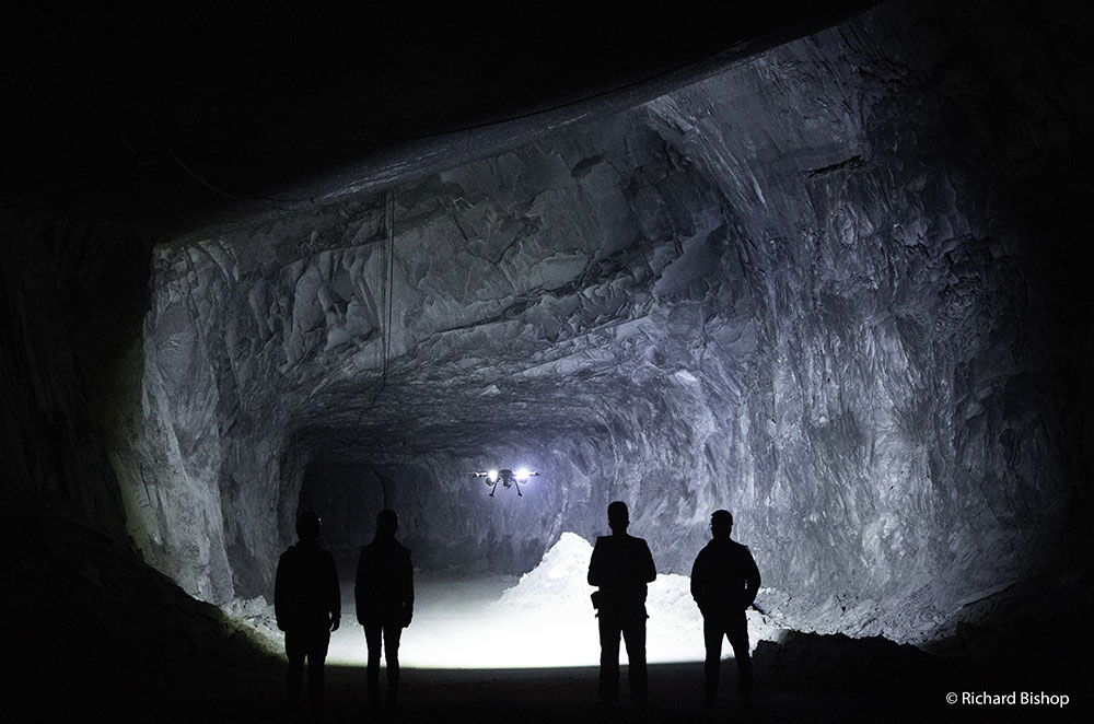 1st place photo by Richard Bishop: Group of mine workers flying a drone into an underground tunnel
