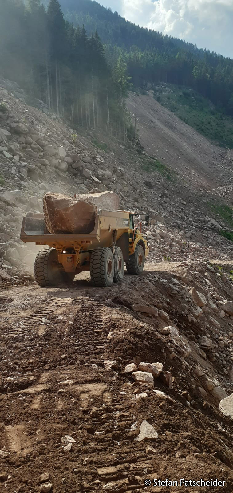 Honorable mention photo by Stefan Patscheider: Mining truck carrying large boulders along a dirt road in a quartz porphyry quarry